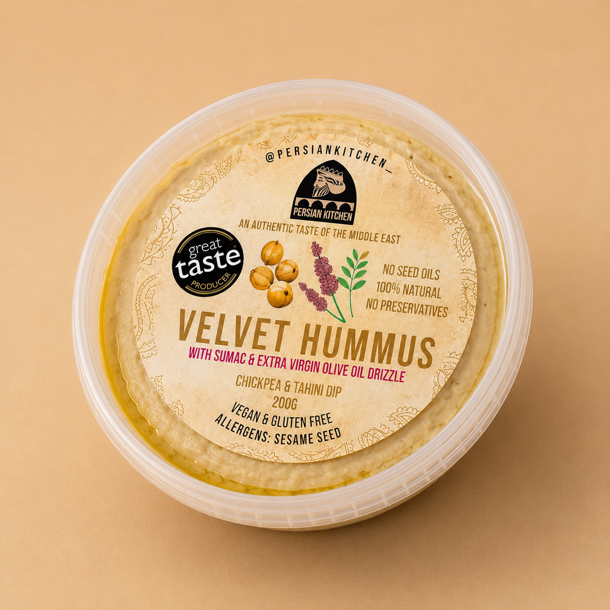 A round clear plastic tub of Persian Kitchen Velvet Hummus with a beige label, photographed from above on a warm beige background.